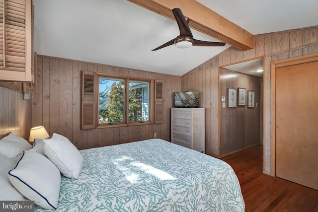 bedroom featuring lofted ceiling with beams, wooden walls, wood finished floors, and a ceiling fan