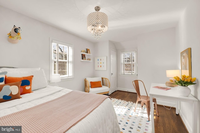 bedroom featuring wood finished floors, baseboards, and a chandelier