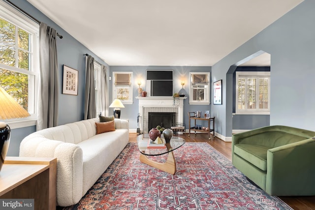 living area with a brick fireplace, baseboards, and wood finished floors