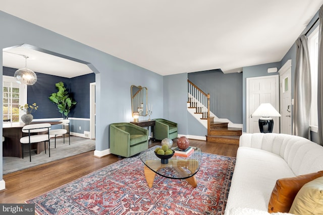 living area featuring baseboards, a notable chandelier, wood finished floors, and stairs