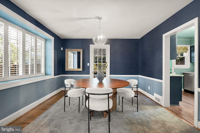 dining space with visible vents, a notable chandelier, wood finished floors, and baseboards