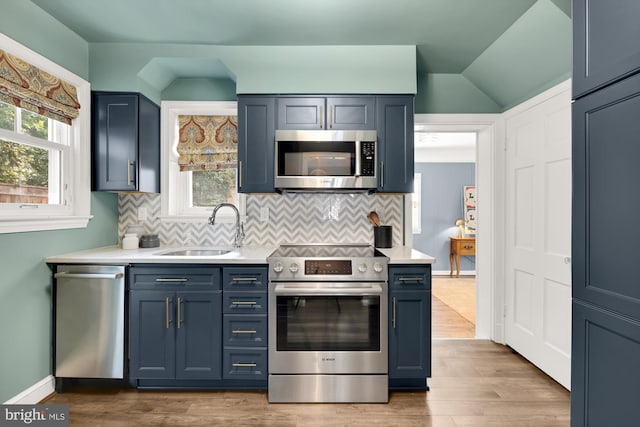 kitchen with wood finished floors, stainless steel appliances, light countertops, and a sink