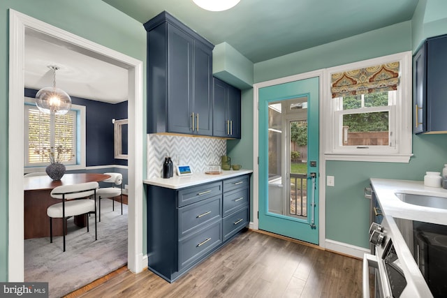 kitchen with a sink, decorative backsplash, wood finished floors, and light countertops