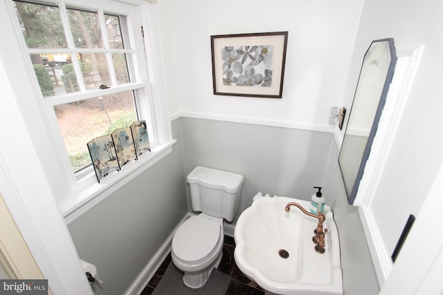 bathroom with a sink, baseboards, plenty of natural light, and toilet