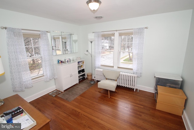 sitting room featuring radiator heating unit, wood finished floors, plenty of natural light, and baseboards