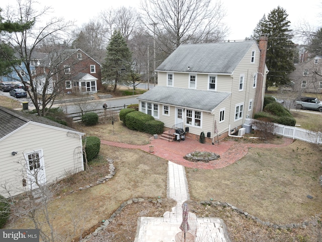 rear view of house with central AC unit, fence, roof with shingles, and a chimney