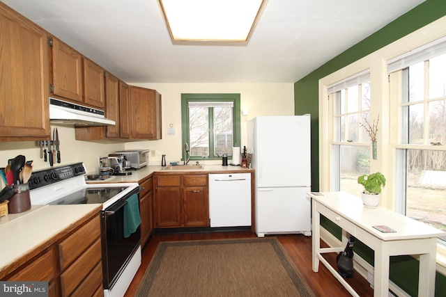 kitchen featuring white appliances, a sink, light countertops, under cabinet range hood, and brown cabinets