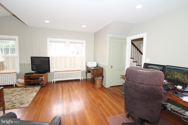 office area with hardwood / wood-style floors, lofted ceiling, and radiator heating unit