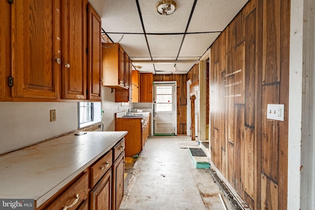 kitchen featuring brown cabinets, wood walls, and a sink