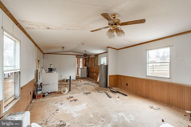 below grade area featuring crown molding, wood walls, water heater, washer / dryer, and wainscoting