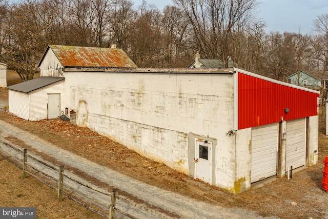 exterior space featuring an outdoor structure, a detached garage, and metal roof