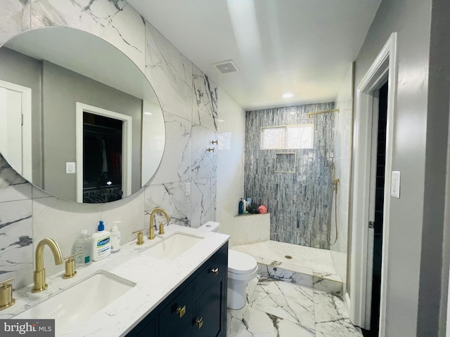 bathroom with visible vents, marble finish floor, a tile shower, and a sink