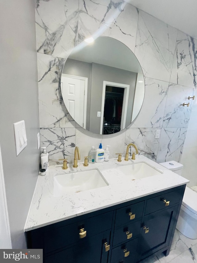 bathroom featuring double vanity, marble finish floor, toilet, and a sink