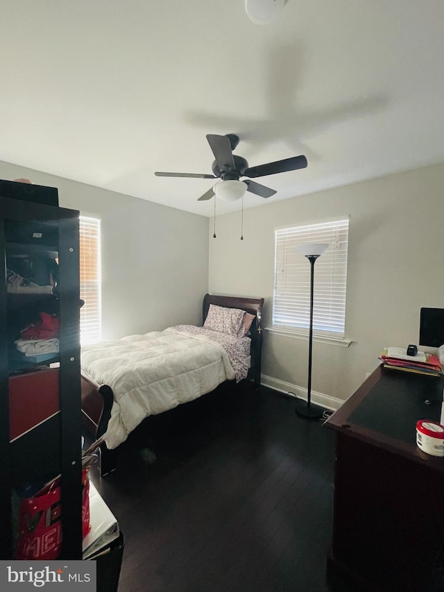 bedroom with dark wood finished floors, a ceiling fan, and baseboards