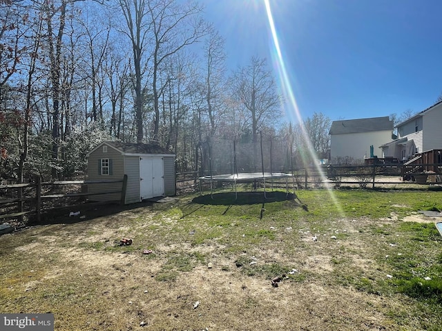 view of yard with a storage shed, an outbuilding, a trampoline, and fence