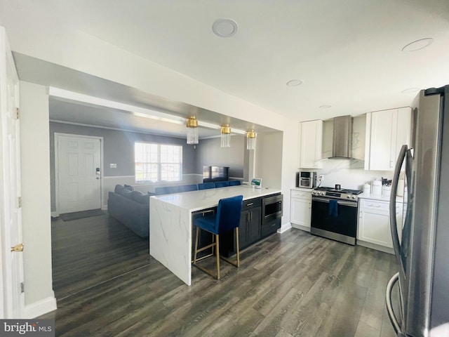 kitchen featuring a peninsula, stainless steel appliances, white cabinetry, wall chimney exhaust hood, and open floor plan