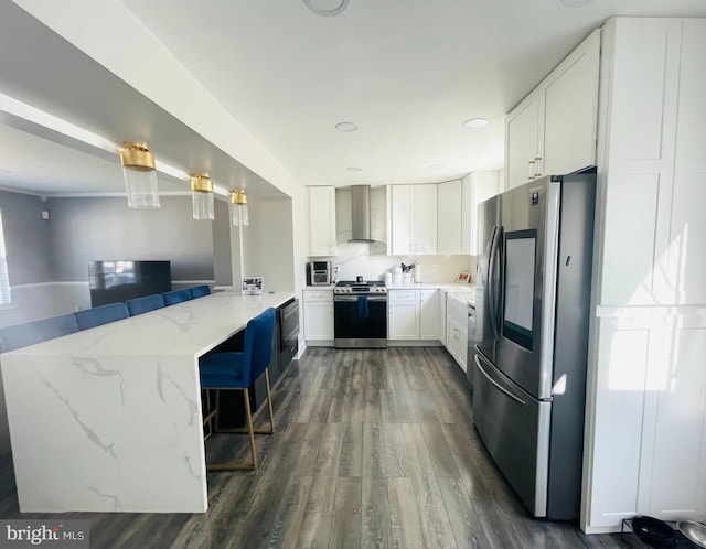 kitchen with dark wood-type flooring, stainless steel appliances, a peninsula, wall chimney range hood, and light stone countertops