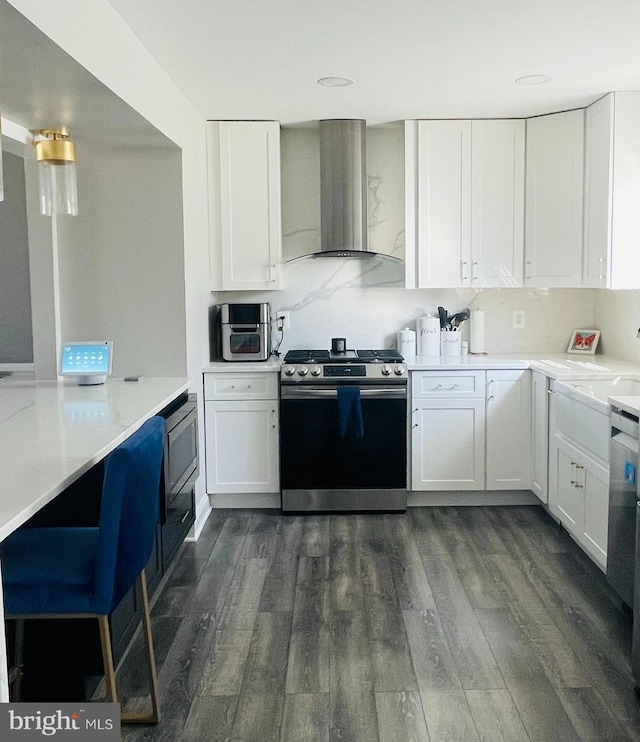 kitchen featuring dark wood finished floors, stainless steel range with gas stovetop, white cabinetry, and wall chimney range hood