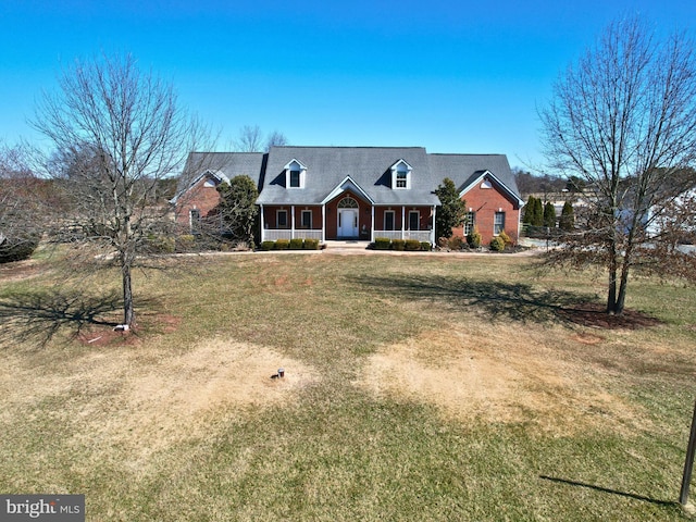 cape cod home featuring brick siding, covered porch, and a front lawn
