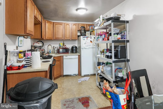 kitchen featuring brown cabinets, white appliances, light countertops, and a sink