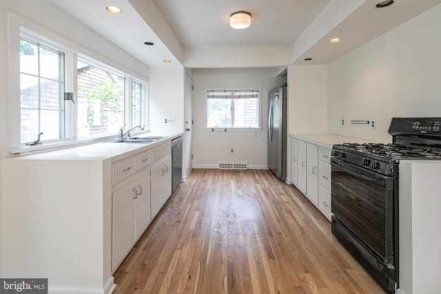 kitchen with a sink, stainless steel appliances, light wood-type flooring, and white cabinets