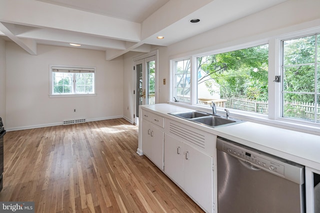 kitchen featuring visible vents, a sink, stainless steel dishwasher, light wood-style floors, and light countertops