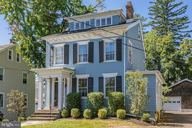 view of front of property featuring stucco siding, an outdoor structure, and a chimney