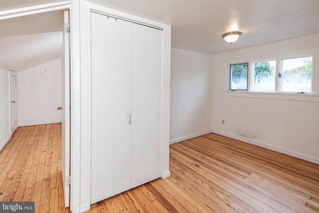 unfurnished bedroom featuring baseboards, light wood-type flooring, and a closet