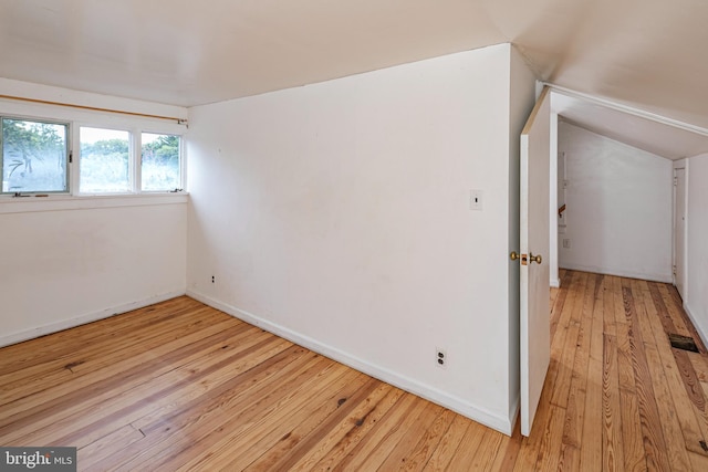 interior space featuring light wood-type flooring, lofted ceiling, and baseboards