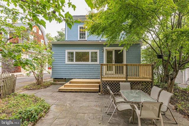 rear view of house featuring a patio area, outdoor dining space, a wooden deck, and fence