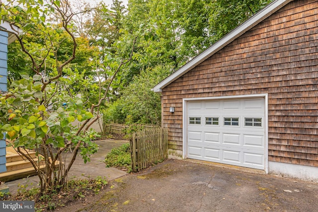 garage with aphalt driveway and fence