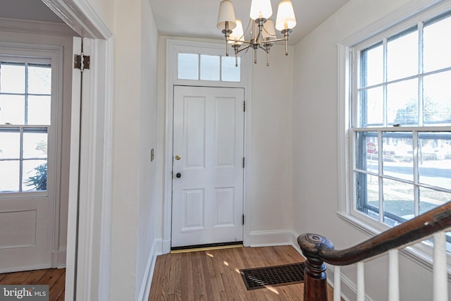 entryway featuring visible vents, baseboards, a notable chandelier, and wood finished floors