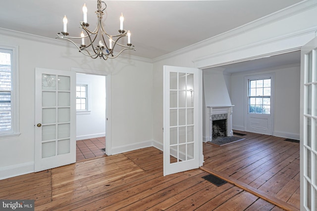 interior space with visible vents, ornamental molding, hardwood / wood-style floors, an inviting chandelier, and baseboards