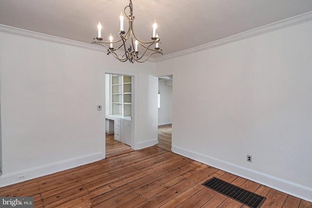 spare room featuring visible vents, ornamental molding, hardwood / wood-style flooring, baseboards, and a chandelier