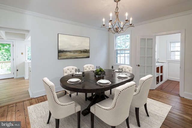 dining room featuring an inviting chandelier, light wood-style flooring, baseboards, and ornamental molding