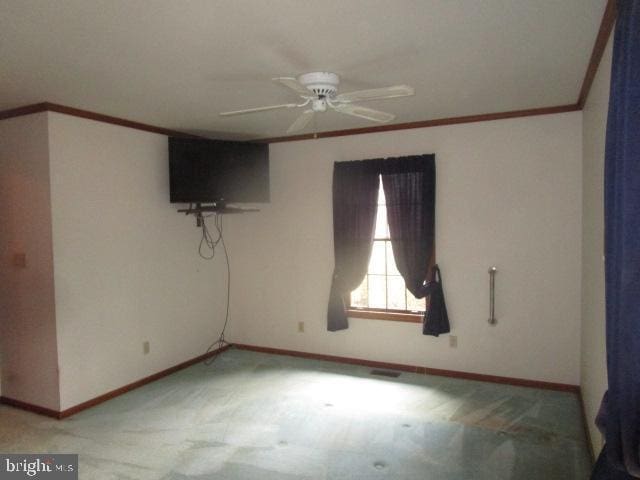 spare room with baseboards, light carpet, a ceiling fan, and crown molding