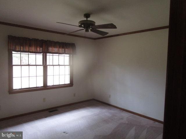 carpeted empty room featuring visible vents, baseboards, ceiling fan, and crown molding