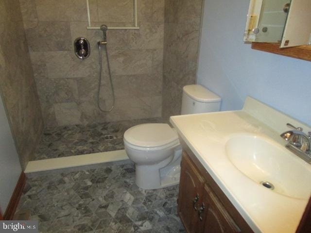 full bath with tiled shower, toilet, and vanity