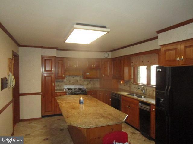 kitchen with a kitchen island, ornamental molding, brown cabinetry, black appliances, and a sink