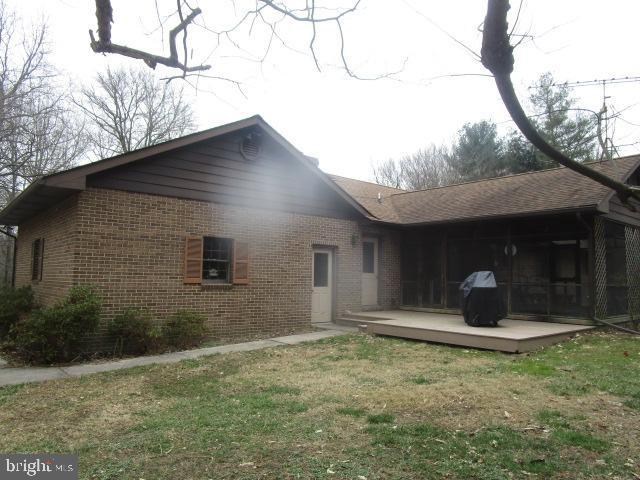 rear view of house featuring a yard, brick siding, and a sunroom