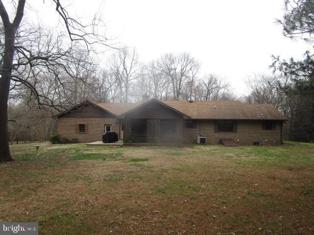 rear view of house featuring a lawn and cooling unit