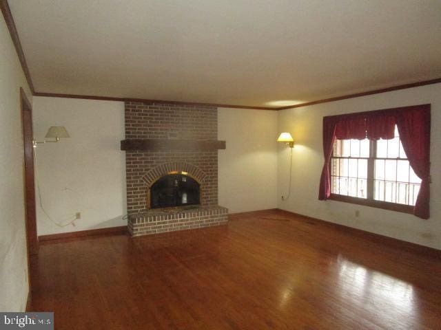 unfurnished living room with wood finished floors, a fireplace, and crown molding