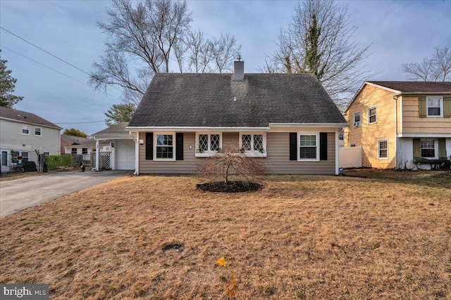 back of property with fence, a yard, a chimney, a shingled roof, and aphalt driveway