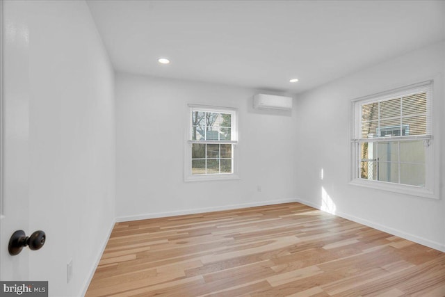 unfurnished room featuring an AC wall unit, recessed lighting, light wood-style floors, and baseboards