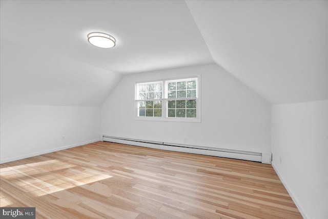 additional living space with baseboards, a baseboard heating unit, lofted ceiling, and wood finished floors