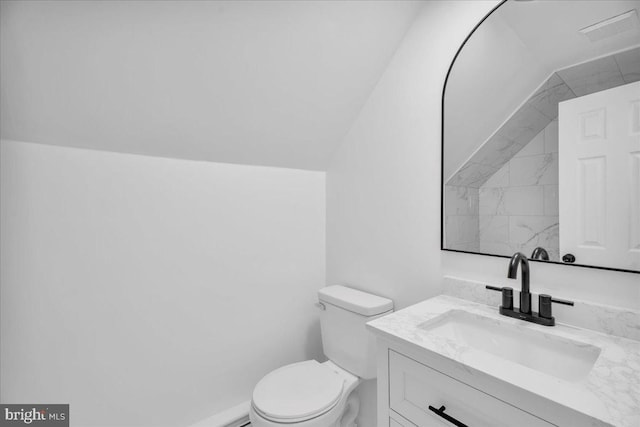 bathroom featuring visible vents, toilet, vanity, and vaulted ceiling