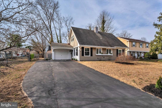 tri-level home featuring a gate, fence, an attached garage, a chimney, and aphalt driveway