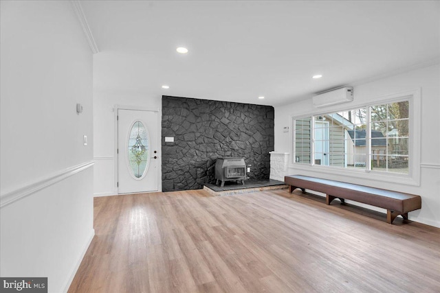 foyer featuring ornamental molding, wood finished floors, a wall unit AC, recessed lighting, and a wood stove