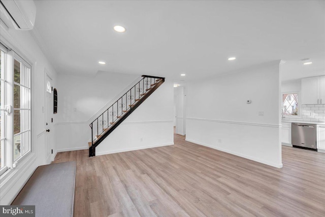 foyer featuring baseboards, recessed lighting, stairs, an AC wall unit, and light wood-style floors