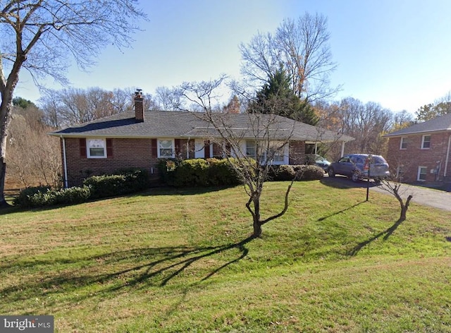 ranch-style home featuring a front yard, brick siding, and a chimney